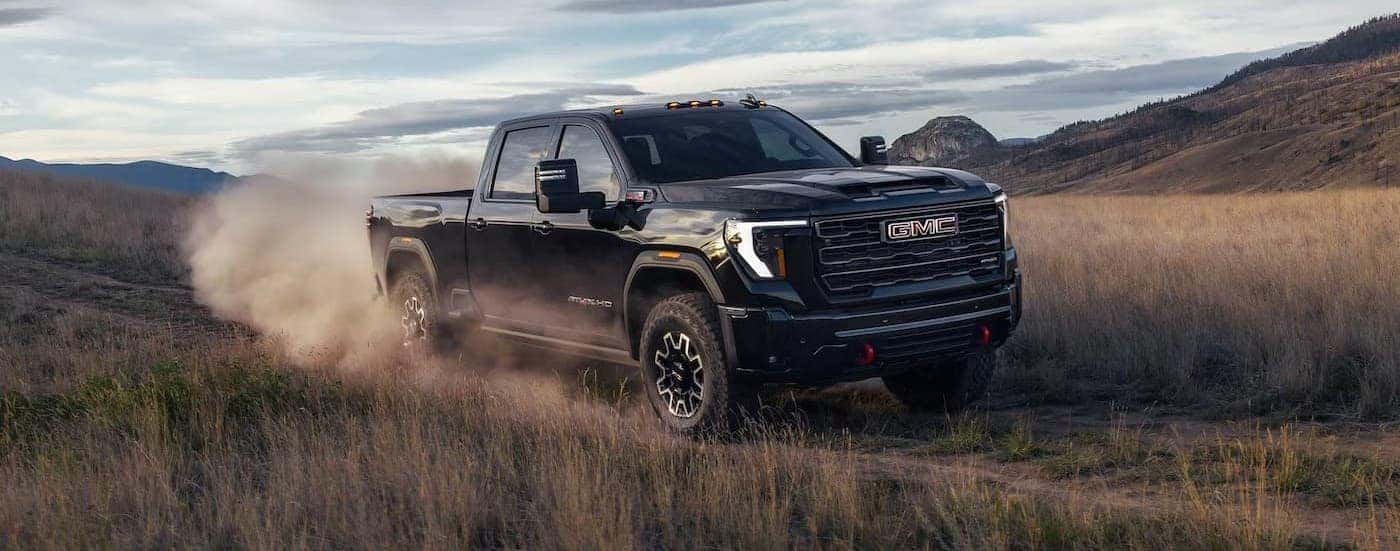 A black 2026 GMC Sierra 2500 driving on a trail.