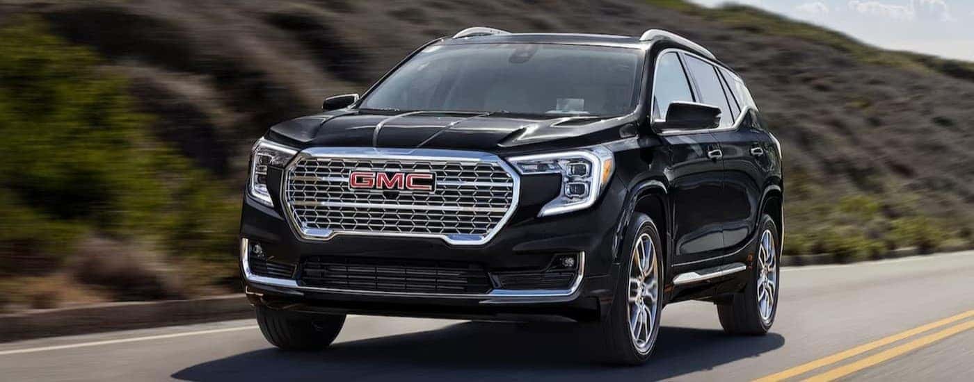 A black 2024 GMC Terrain driving on a highway.