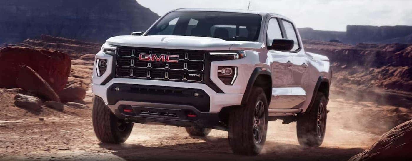 A white 2024 GMC Canyon AT4 driving offroad.