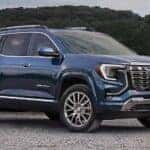 A blue 2026 GMC Terrain Denali parked near a house.