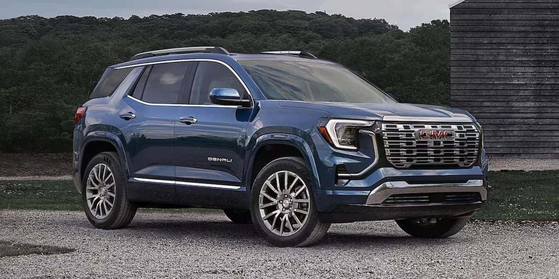 A blue 2026 GMC Terrain Denali parked near a house.