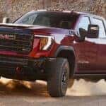 A red 2025 GMC Sierra 2500 AT4 off-roading on sand