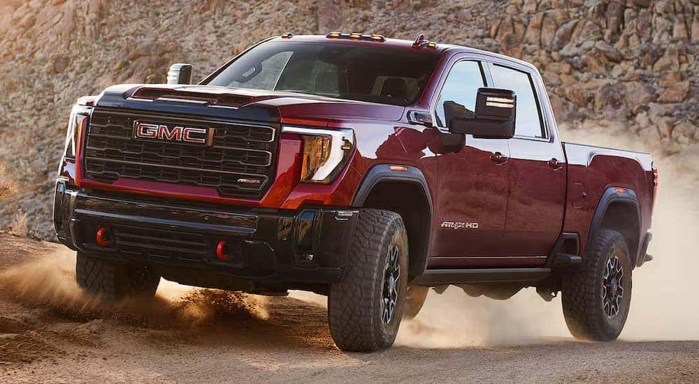 A red 2025 GMC Sierra 2500 AT4 off-roading on sand