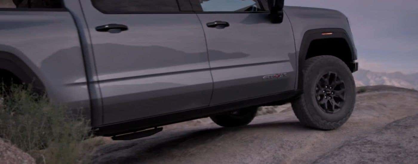 Grey 2027 Sierra 1500 AT4X with 35" MT Tires driving off-road.