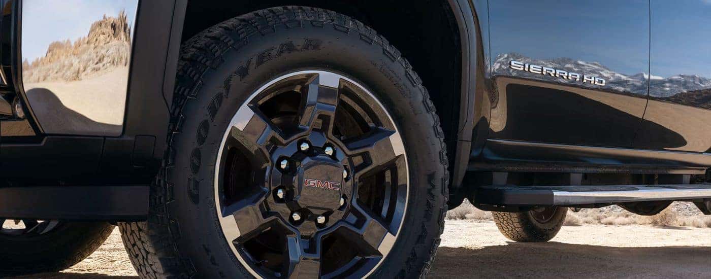 Close up of a tire and wheel on a black GMC Sierra 2500 HD.