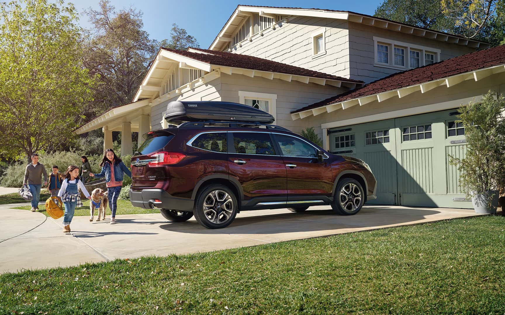 A family runs from their house to get into their Ascent Touring in Dark Mahogany parked in the driveway