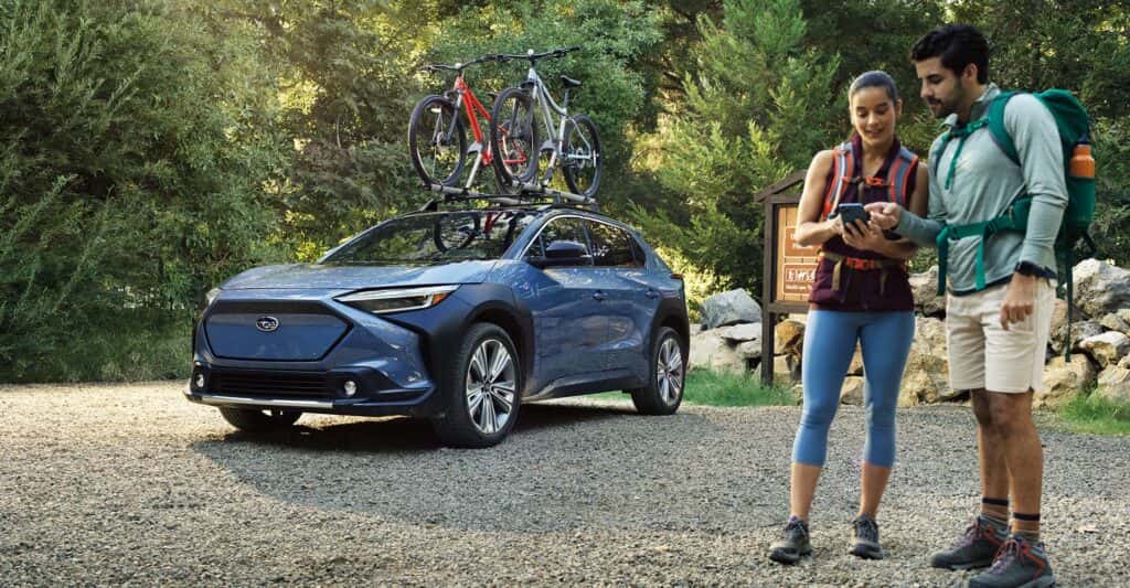 A couple at a trailhead looking at a device with 2023 Solterra in the background with bikes on top