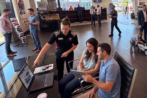 Sales team assisting customers near a vehicle on the Serra Toyota Lincolnwood showroom floor