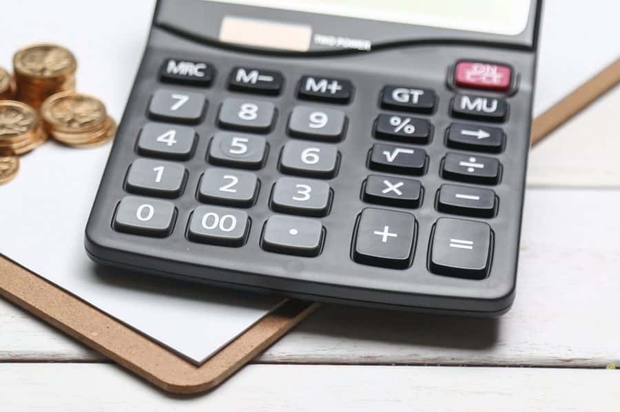 A calculator and a small stack of coins on a clipboard