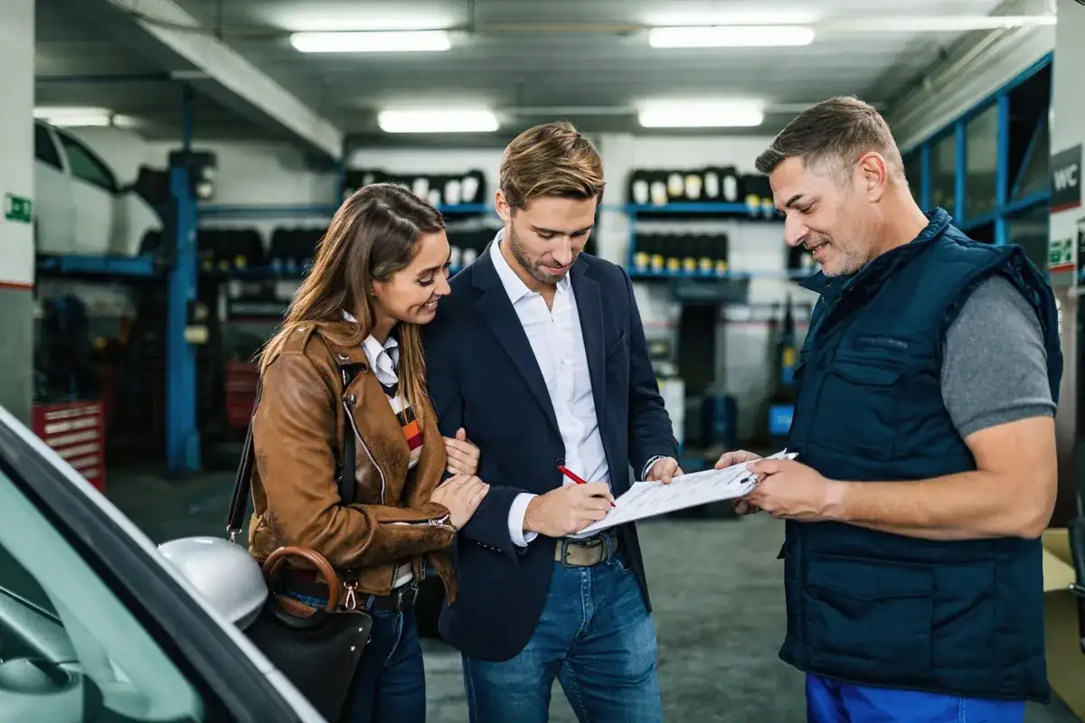 Service advisor reviewing paperwork with a couple at a service center