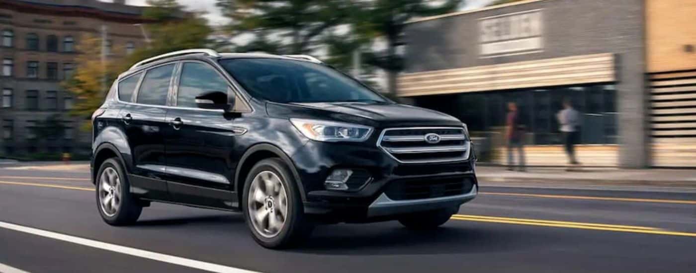 A black 2019 Ford Escape driving downtown.