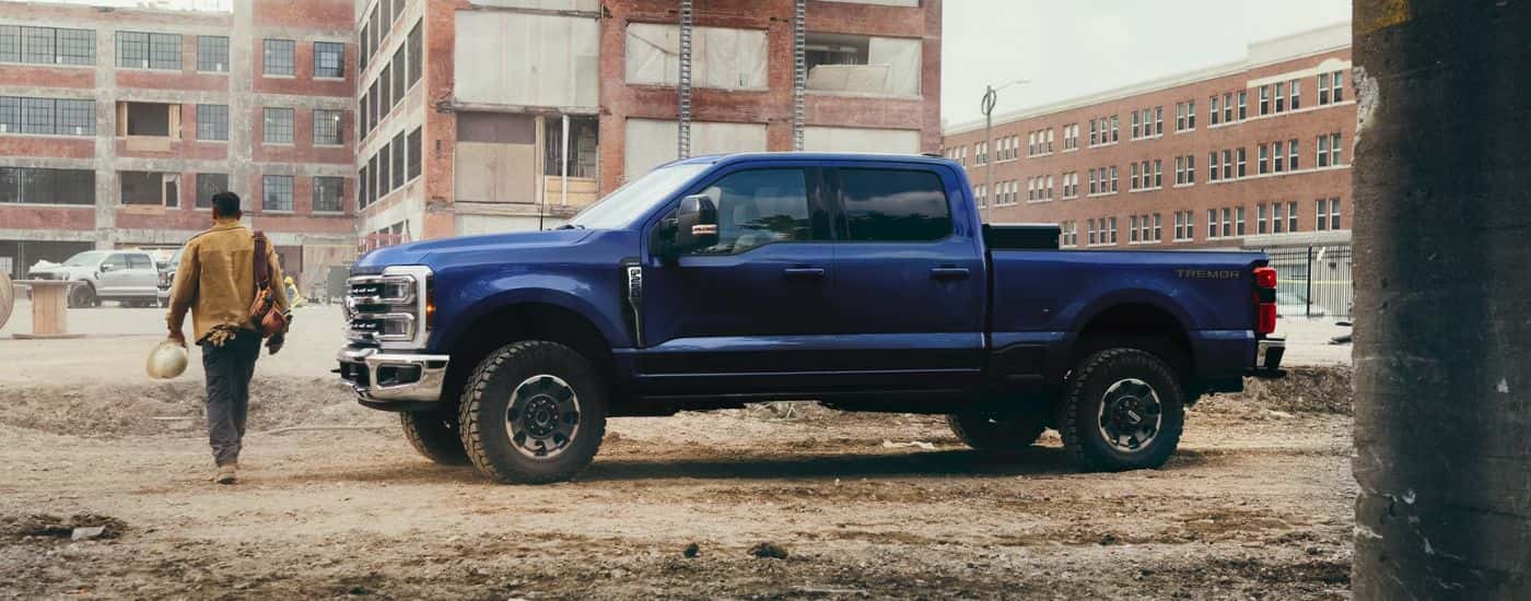A blue 2026 Ford Super Duty F-250 Lariat shown parked by a person on a construction site.