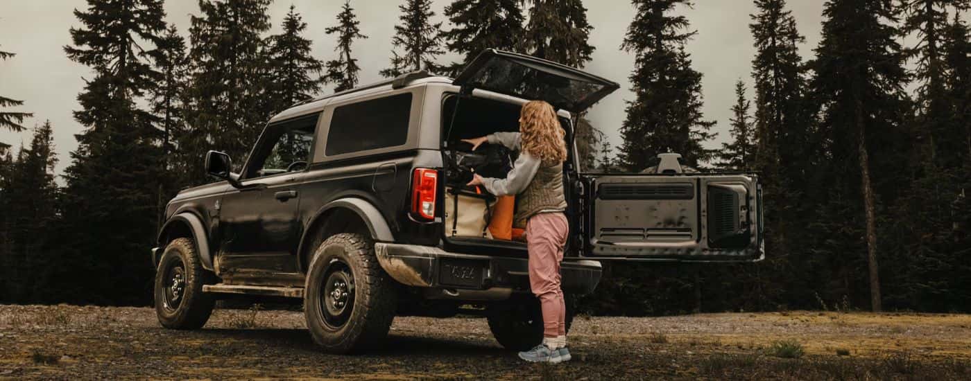 Rear view of a black 2026 Ford Bronco with a woman loading the cargo area.