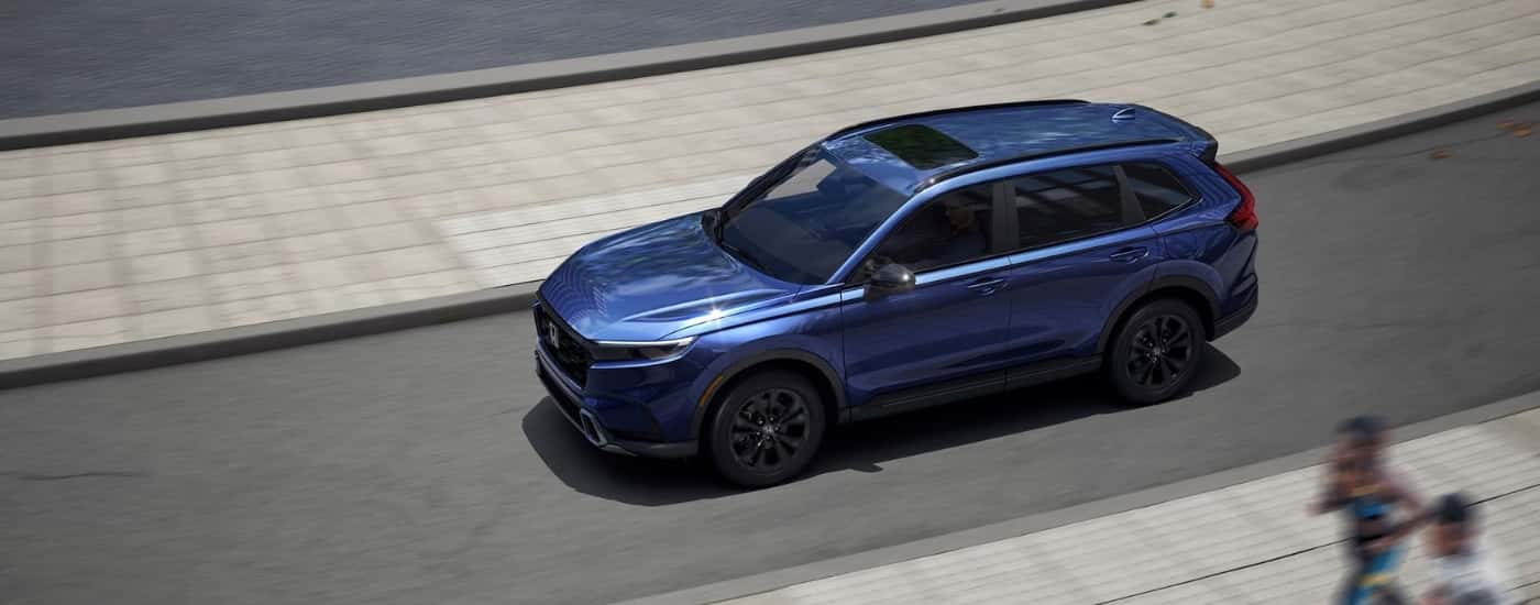 Blue 2026 Honda CR-V Hybrid Sport Touring driving on a city street