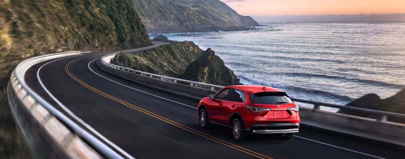 A red 2023 Honda HR-V EX-L driving by the ocean.
