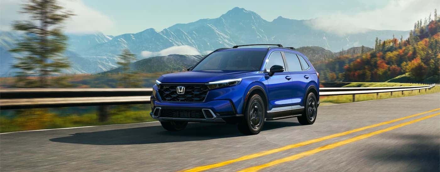 Blue 2023 Honda CR-V driving along a mountainous road