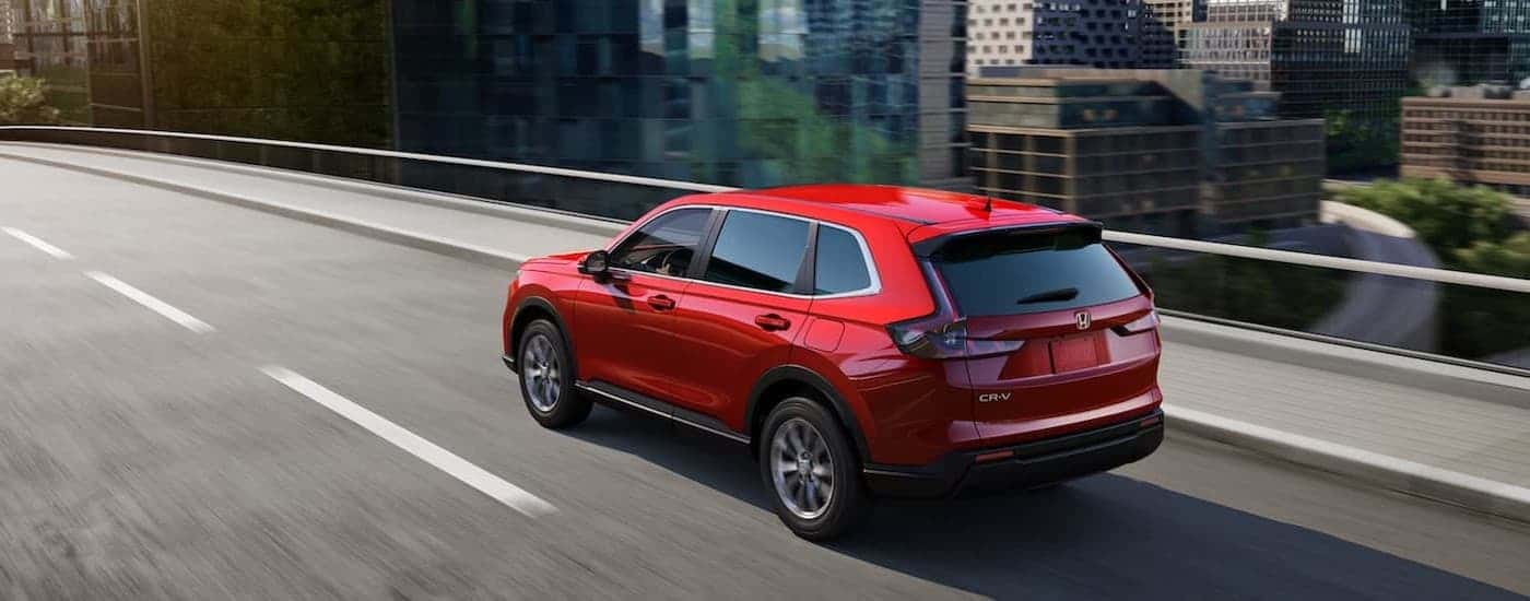 A red 2024 Honda CR-V riving on a bridge.