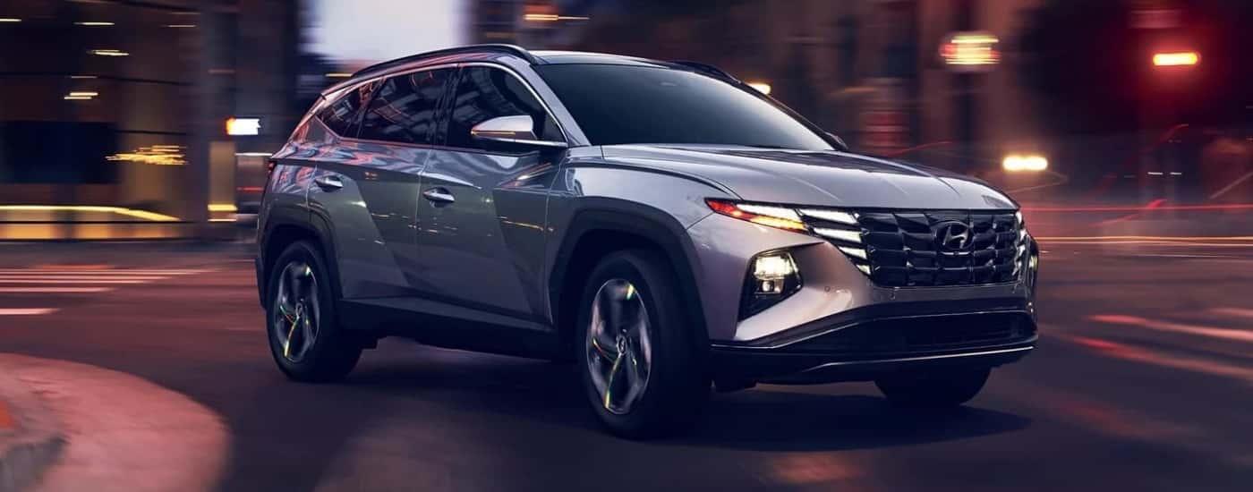 Silver 2023 Hyundai Tucson driving through an intersection