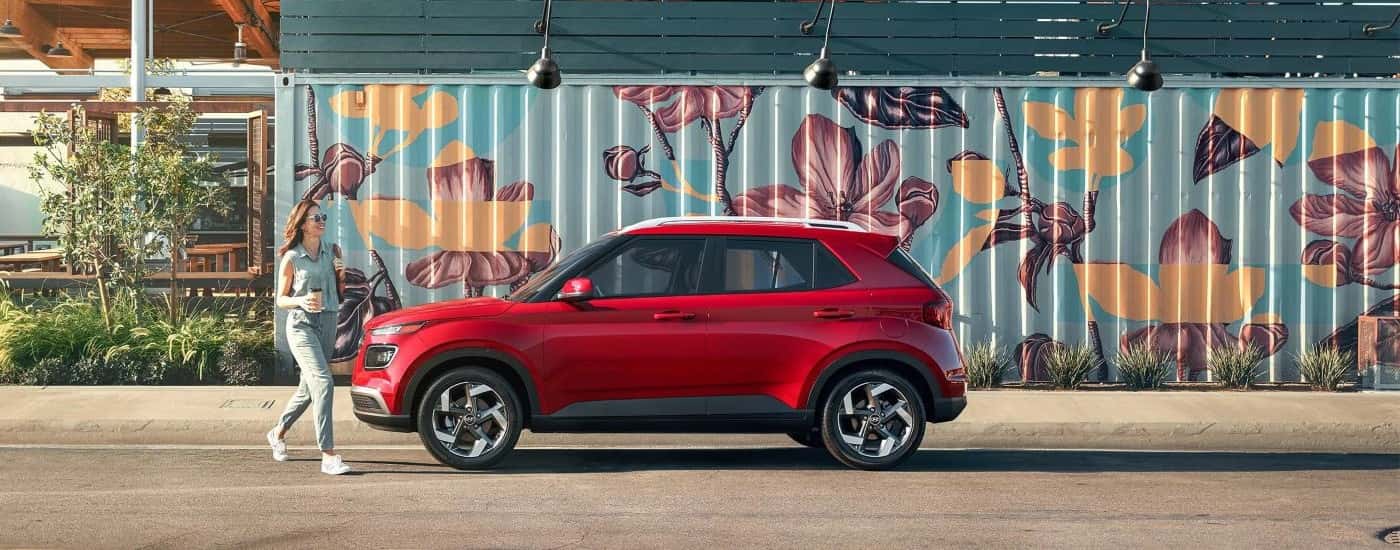 Side of a red 2026 Hyundai Venue parked by a wall.