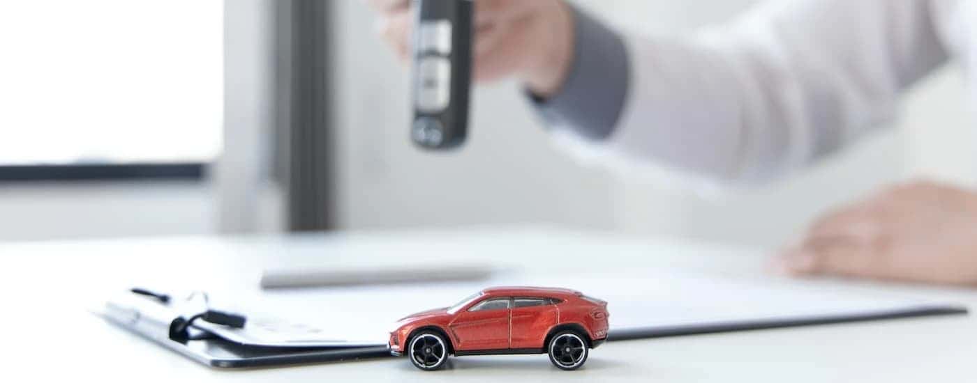 Person holding an FOB over car loan paperwork