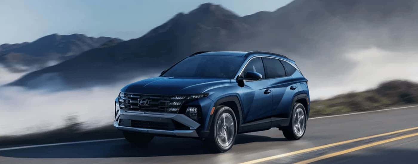 A blue 2026 Hyundai Tucson driving on a highway.