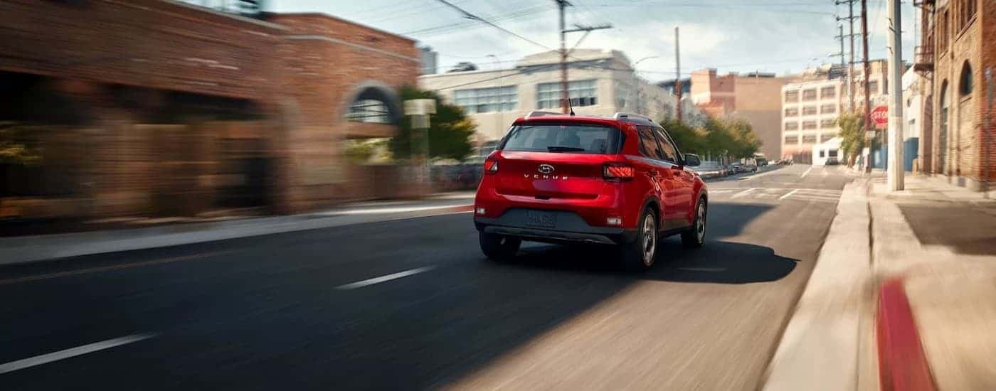 A red 2026 Hyundai Venue driving in a city.