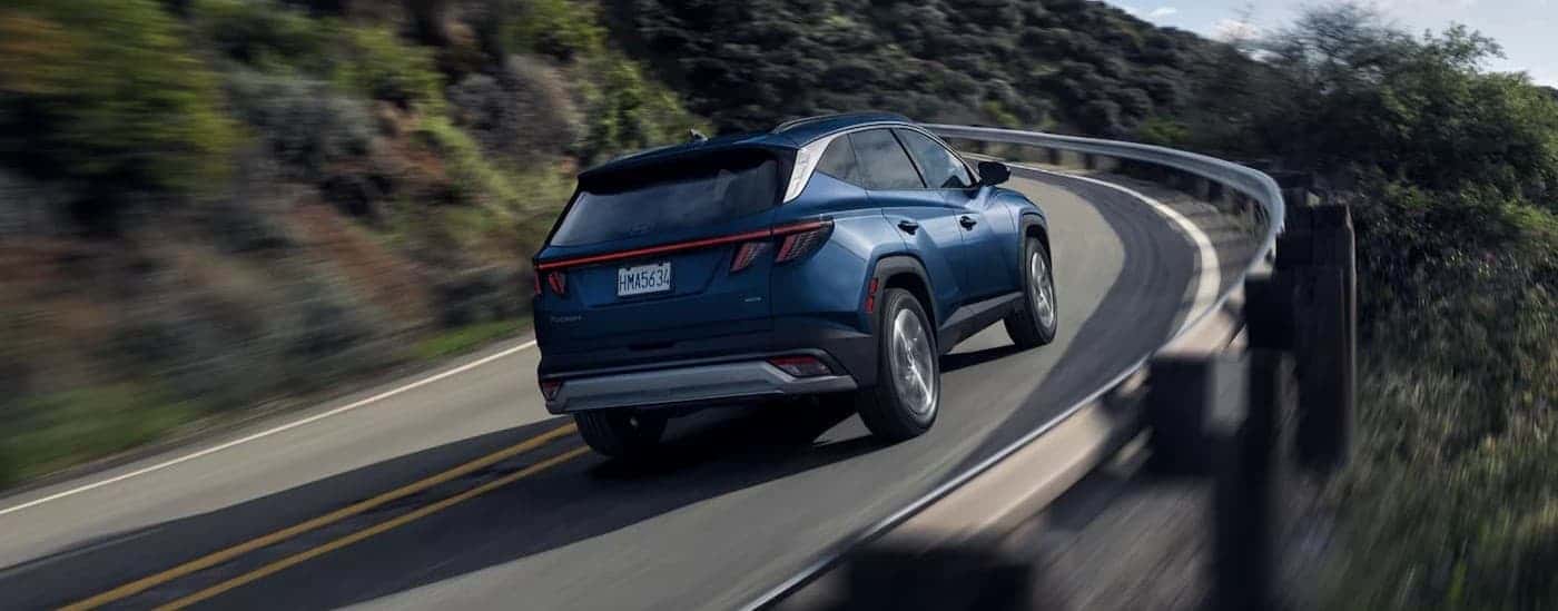 A blue 2025 Hyundai Tucson driving on a highway.