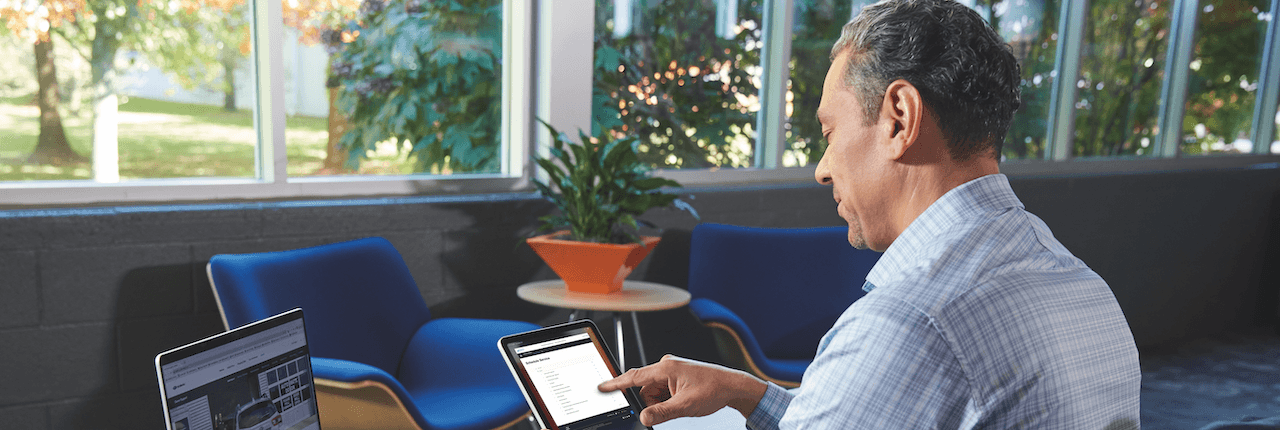 man sitting at desk looking at tablet