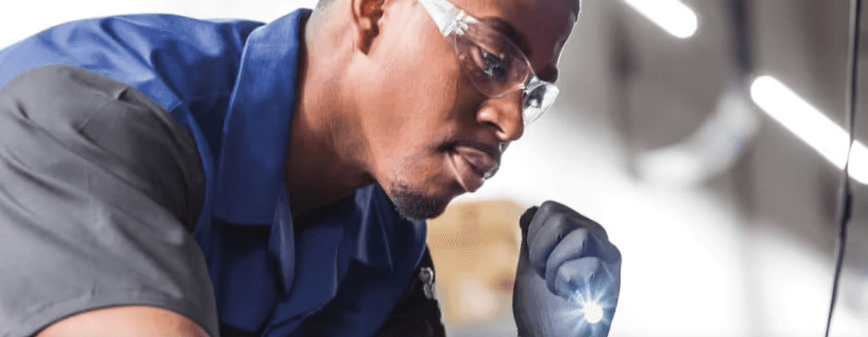Mechanic inspecting vehicle with flashlight
