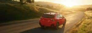 2022 Subaru Crosstrek driving on a country road into the sunset