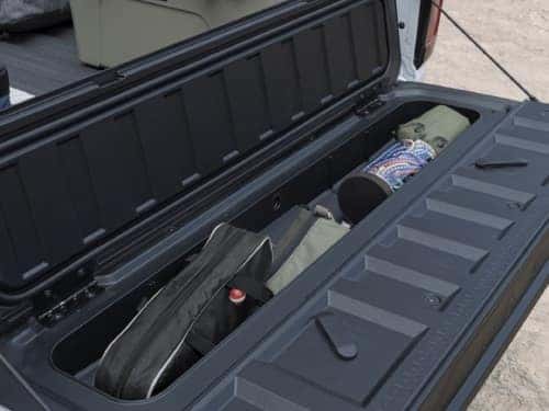 2024 GMC Canyon close up view of multistow storage in tailgate full of camping supplies