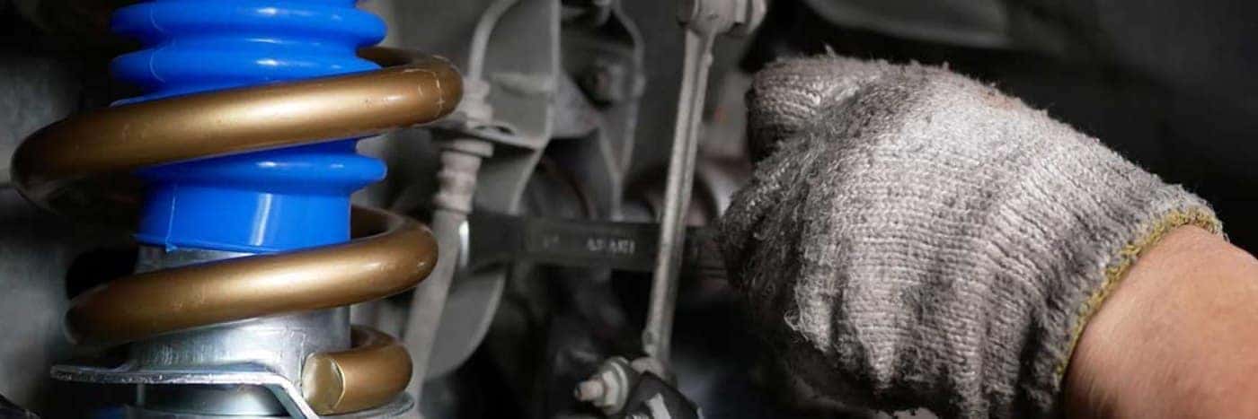 Close up view of a service tech checking out a vehicle's suspension