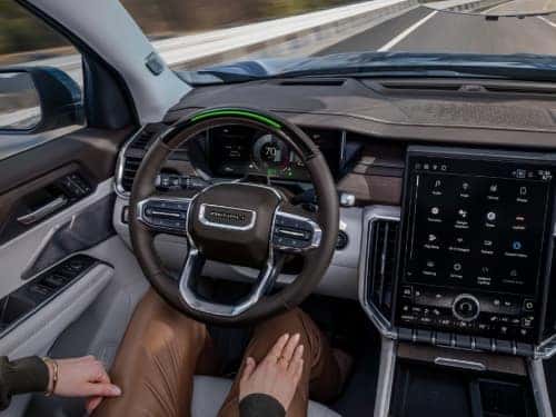 2024 GMC Acadia Denali view of man in driver seat with hands off of wheel while vehicle is in super cruise mode
