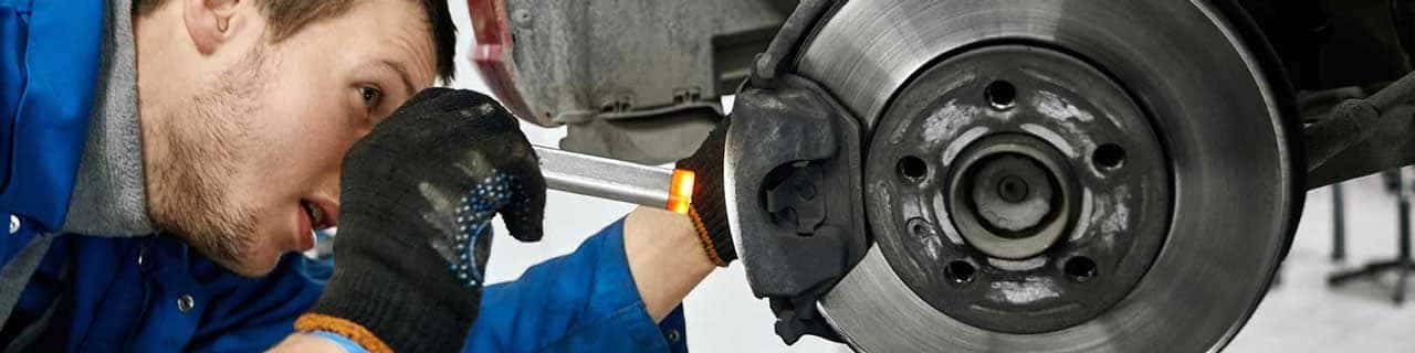 Close up view of a service tech inspecting a vehicle's brake pad