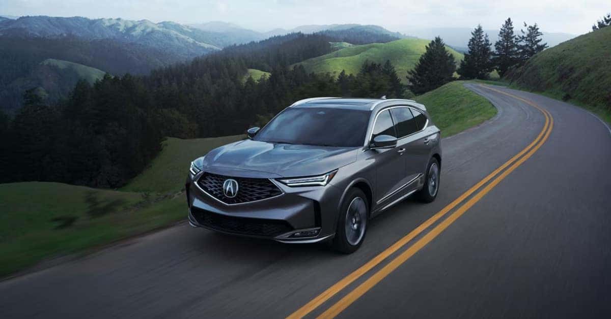driving along a winding two-lane road through rolling green hills and forested mountains
